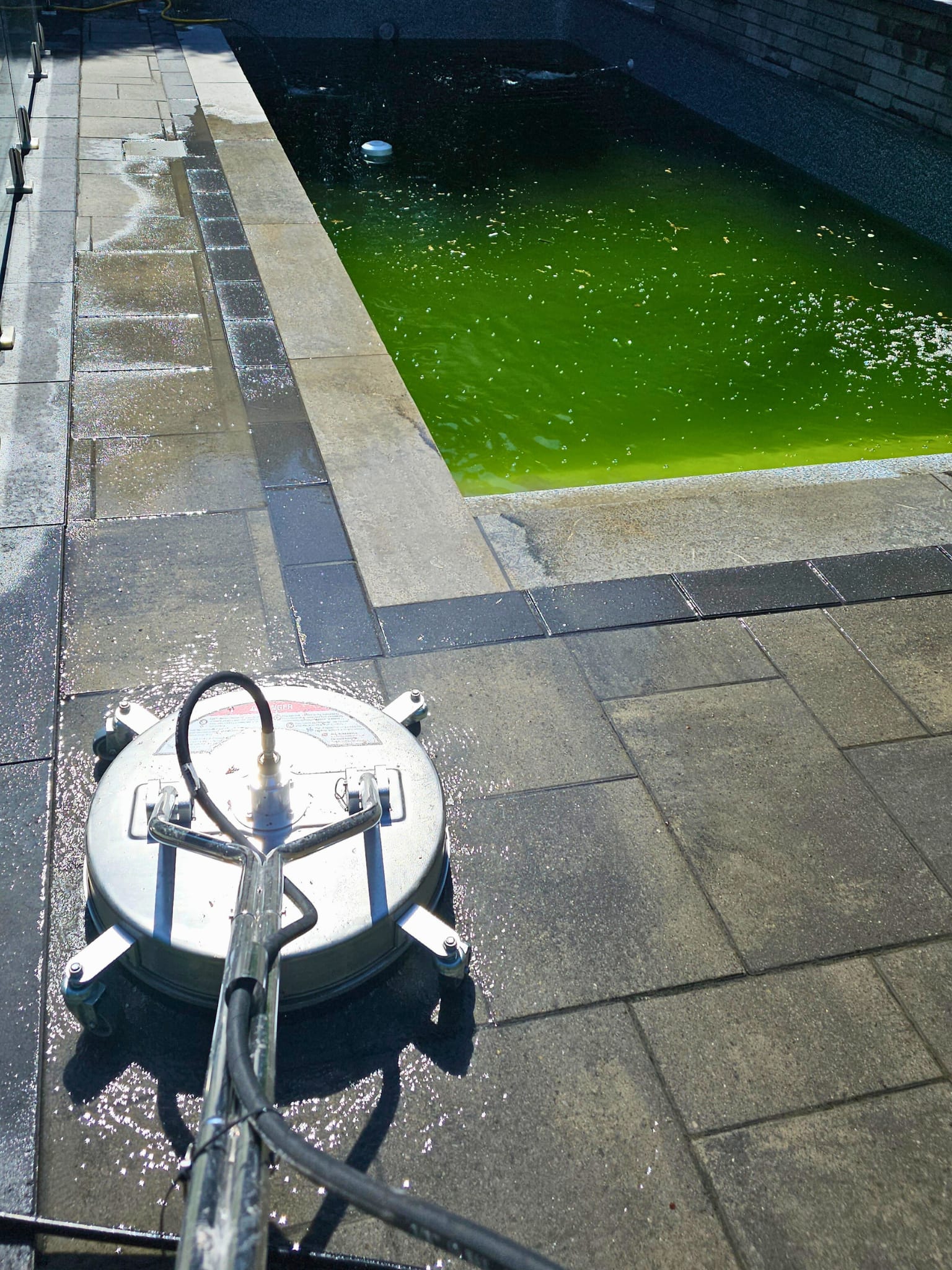 Industrial surface cleaner on flagstone pavers beside pool being treated