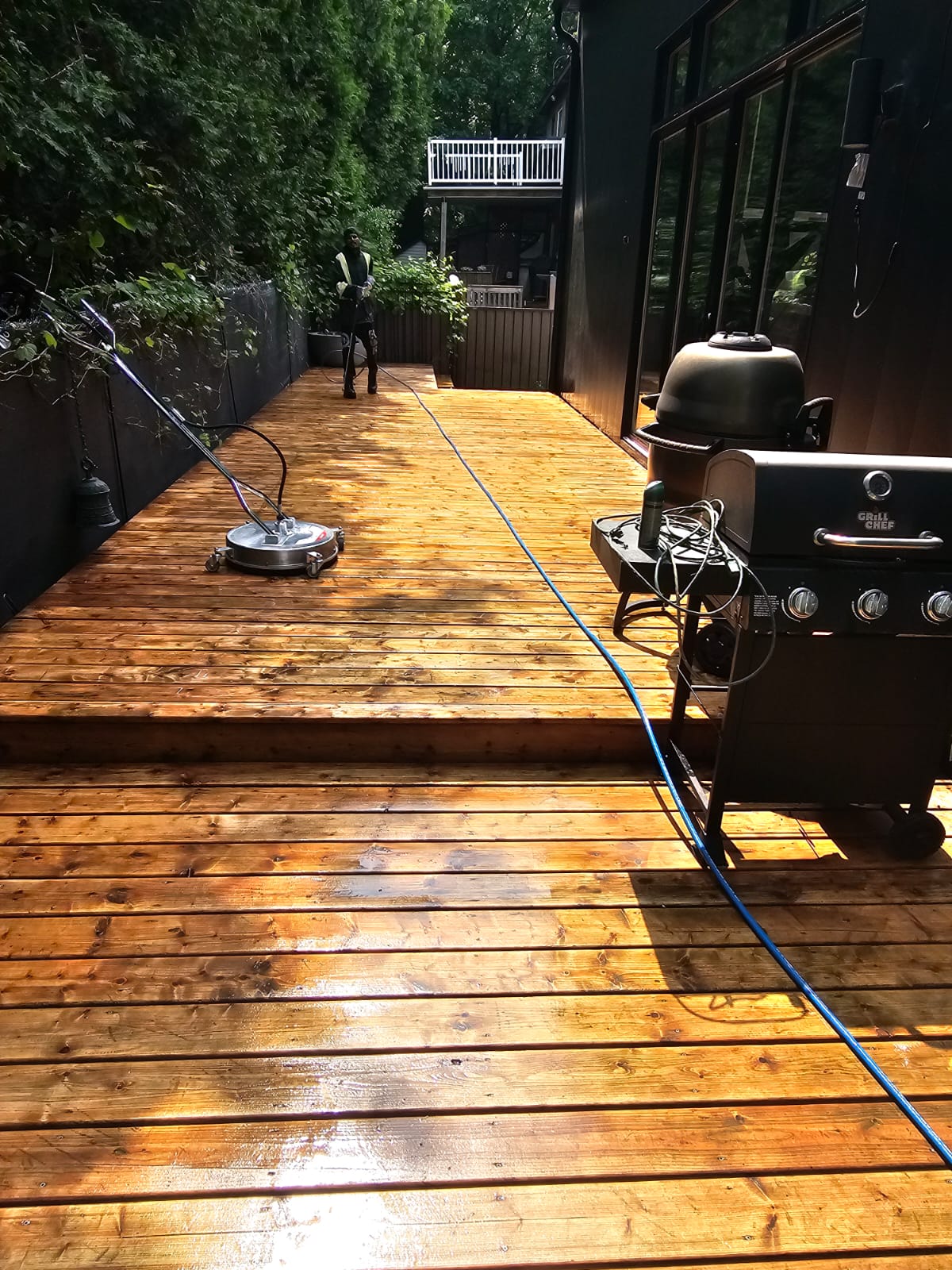 Golden wood deck restored by pressure washing with BBQ grill on outdoor patio